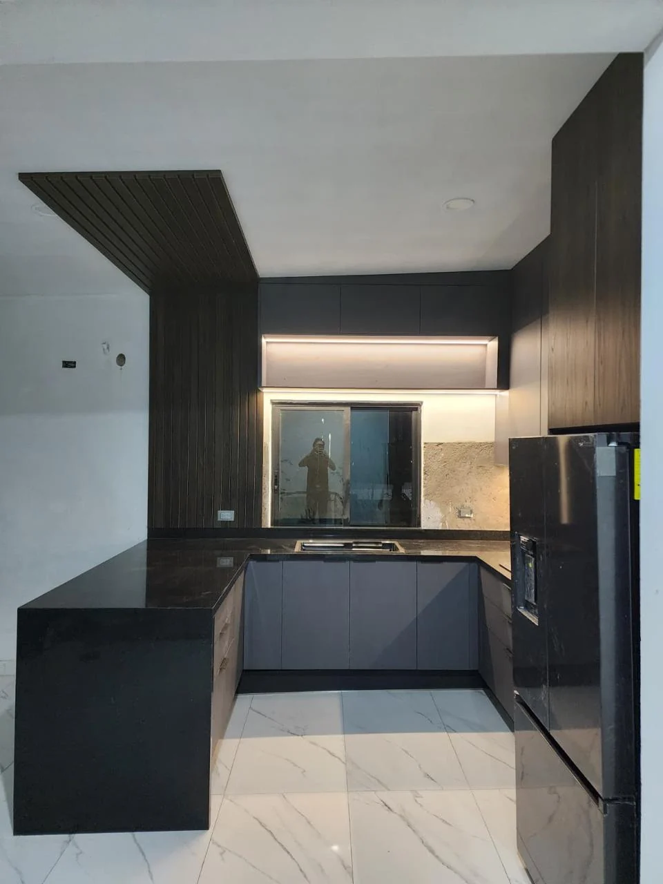 Zona de tarja de cocina integral a medida con cubierta oscura y ventana en Altata, Navolato