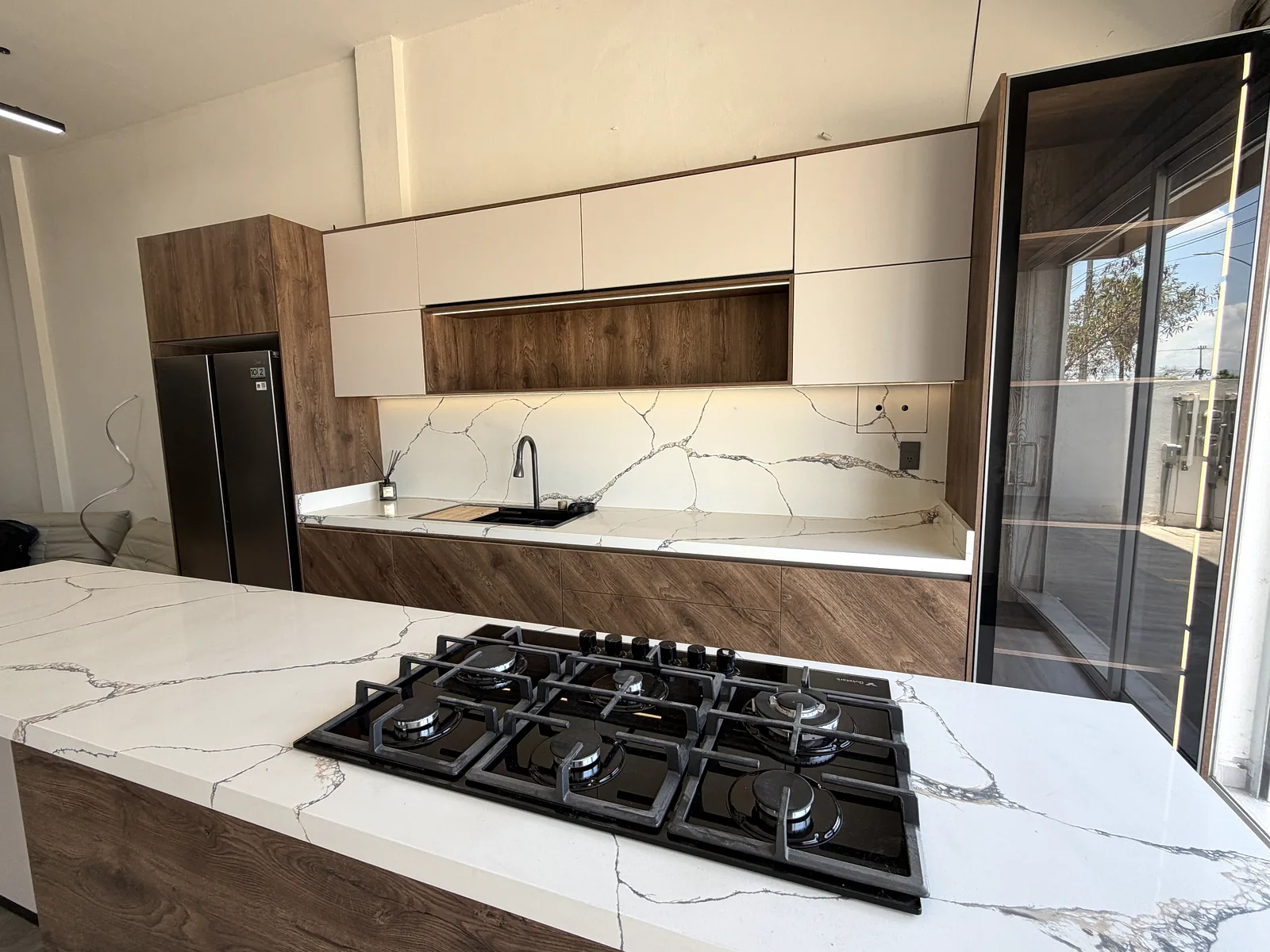 Cocina de exhibición con isla: frente lineal con tarja y torre de refrigerador