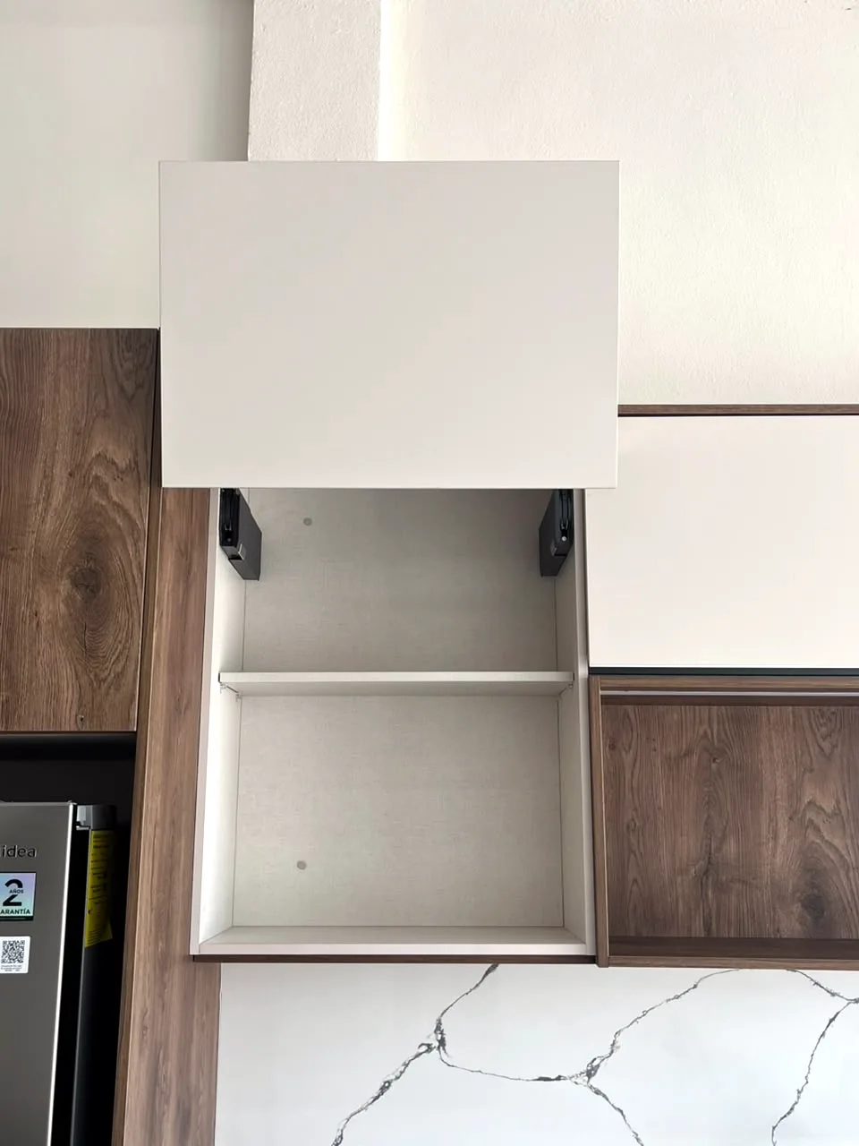 Puerta elevable Blum AVENTOS abierta mostrando la repisa interior del módulo alto