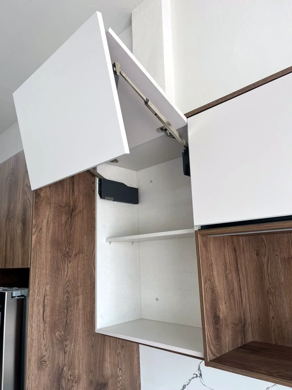 Módulo alto con puerta elevable Blum AVENTOS abierta en la cocina de exhibición de Zeder Cabinet Studio
