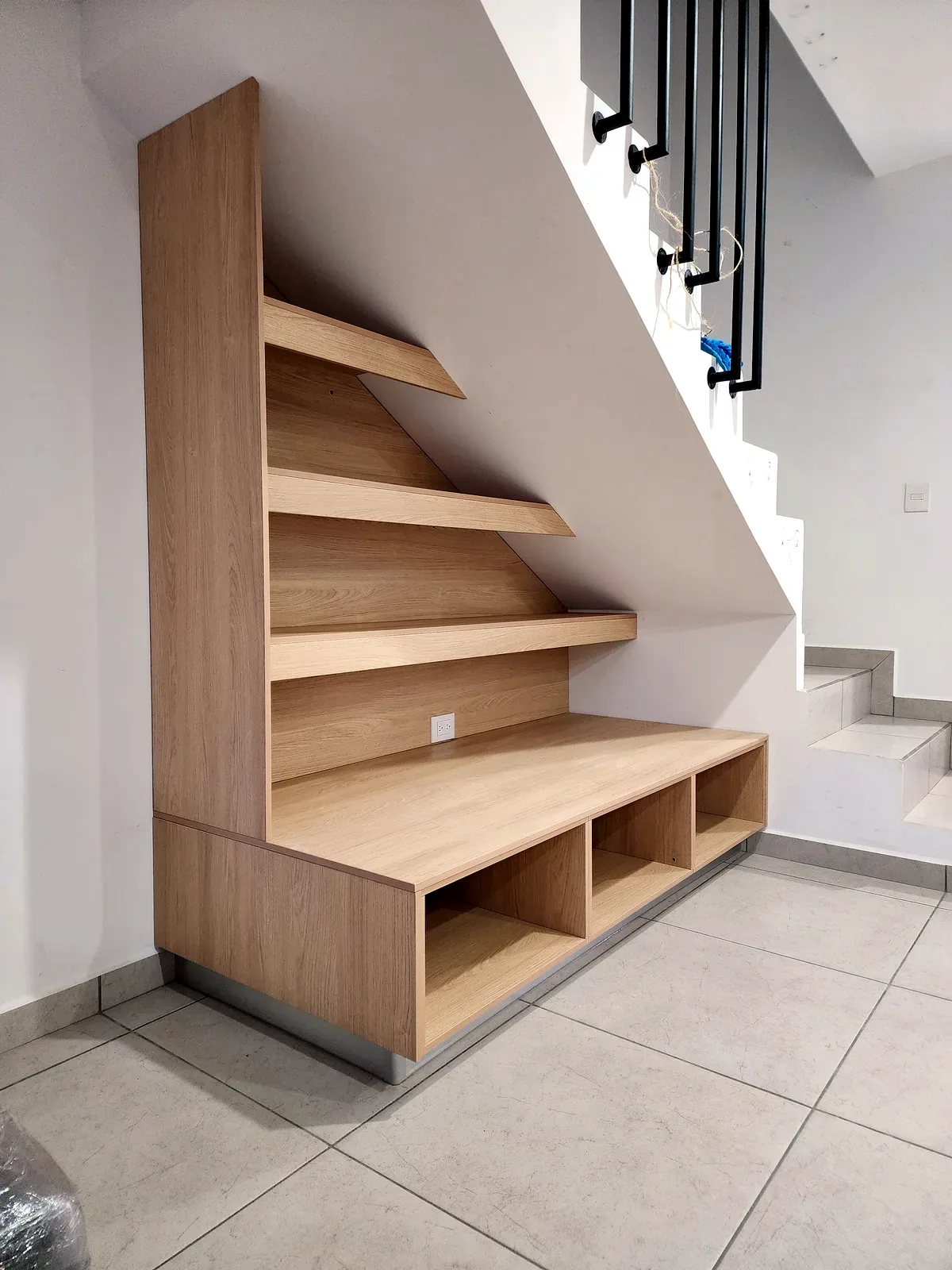 Mueble a medida adaptado a escalera con repisas abiertas y compartimentos inferiores