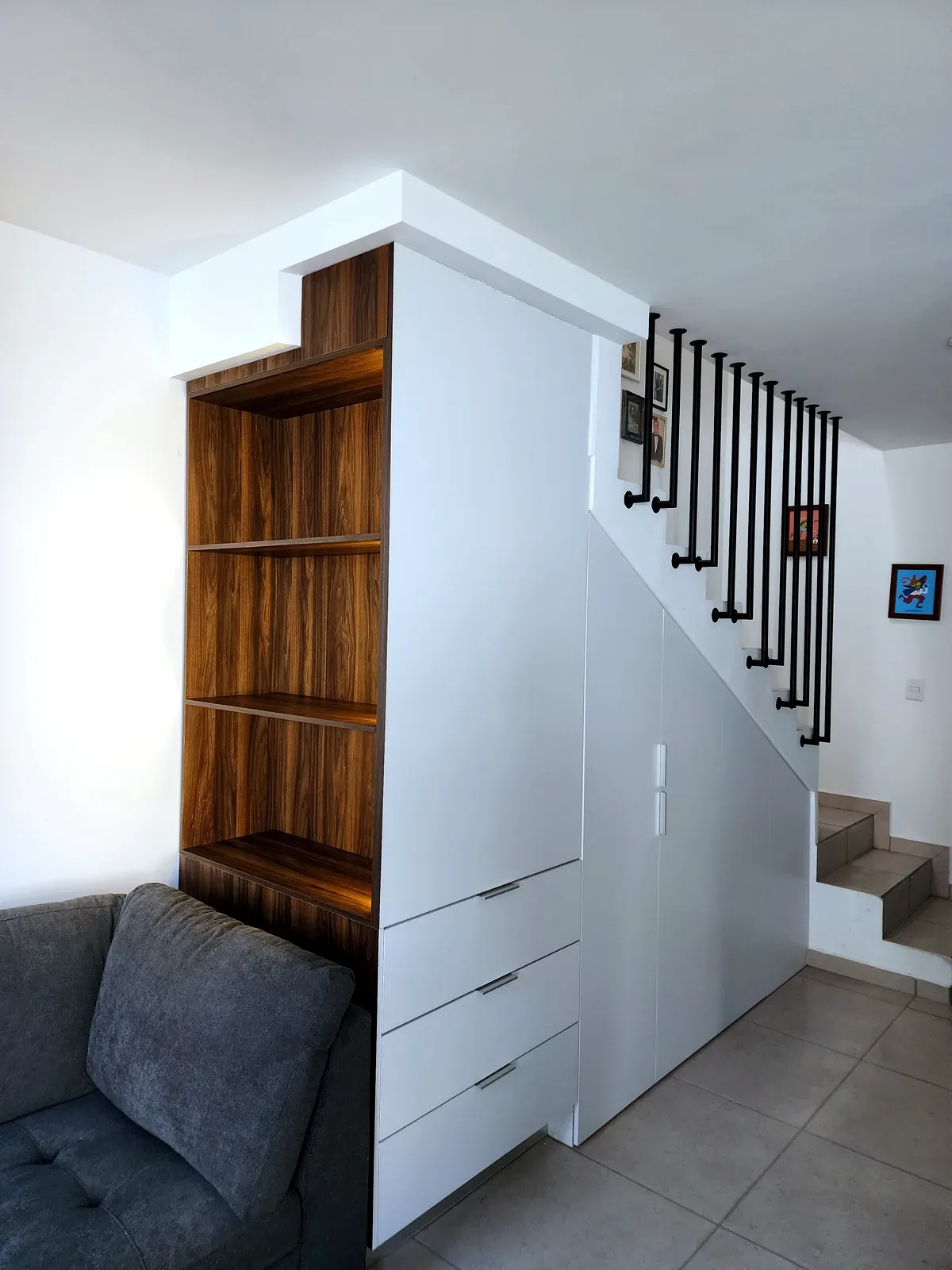Almacenamiento bajo escalera con módulos blancos y nicho tipo madera en Culiacán